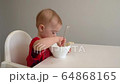 a little girl in a red dress eats porridge in the kitchen 64868165