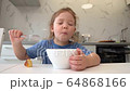 A small child eats healthy food from a white plate 64868166