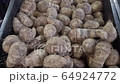 Zoom out on a pile of raw, unpeeled tropical Eddoes, Colocasia antiquorum, on a market stall in the UK 64924772