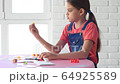 The girl alone plays board games at home and dropped the chip on the floor 64925589