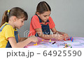 Two sisters enthusiastically play board games at home 64925590