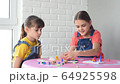 Two girls at home playing board games while sitting at the table 64925598