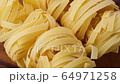 Close-up fettuccine pasta rotating on wooden table. View above on ingredient for pasta 64971258