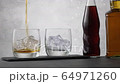 Pouring whiskey in glass with ice cubes on background two bottle with cola and alcohol 64971260