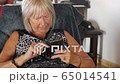 Senior woman looking on mobile phone relaxing on sofa at home, fuerteventura spain 65014541