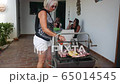 happy elderly lady cooking on a barbecue together with her family 65014545