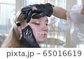 Beautiful stylish trendy eye makeup. Evening make-up on the girl's face, to go to the party. Beauty industry, the master works in gloves with professional cosmetics 65016619