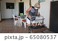 elderly lady cooking on a barbecue with face mask 65080537