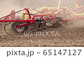 cultivator plows the ground on the field in the summer 65147127