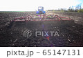 red cultivator plows the ground on the field 65147131