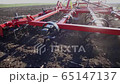 red cultivator plows the ground on the field in the spring 65147137