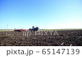 tractor with a cultivator rides on the field in spring 65147139