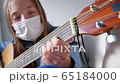Playing guitar at home in quarantine time. Young girl stay at home alone. Detail shoot 65184000