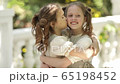 Two sister friends cuddle and kiss each other on the cheek 65198452