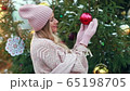 A girl in a pink sweater holds a Christmas tree toy on the street 65198705