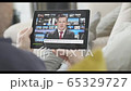 Person watching live stream news broadcast from sofa with business news during the great lock down economic crisis, newscaster, wireless technology, digital tablet 65329727