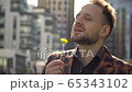 Portrait of joyful young man who sniffs flower, twists it and enjoys life. the concept of peace of mind 65343102