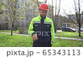 A young man doubts the thought of the work. Builder shows what's wrong with finger down. 65343113