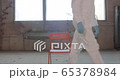 Portrait of young male scientist in protective suit sitting on a chair then leaving the shot in an abandoned factory during pandemic coronavirus quarantine time with big windows in background 4K 65378984