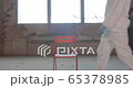 Portrait of young male scientist in protective suit entering the shot and sitting on a chair in an abandoned factory during pandemic coronavirus quarantine time with big windows in background 4K 65378985