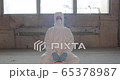 Portrait of young male scientist in protective suit sitting in an abandoned factory during pandemic coronavirus quarantine time with big windows in background 4K 65378987