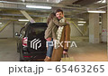 A man stands in the parking lot with his daughter in his arms 65463265