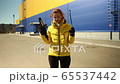 Woman shows the parts of a jack-screw and goes to change a wheel 65537442