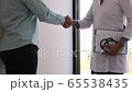 The doctor and the patient congratulate the shaking hands in front of the office at the hospital. 65538435