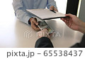 The operator employee submits documents contract and money to the manager while the manager denies the bribe. 65538437