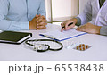Doctor is explaining the medical documentation to the patient and submitting the document to the patient to sign the consent. 65538438