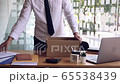 Young male employee standing near work table putting his stuff from in carton box belongings after being dismissed resignation leave company. 65538439
