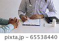 Asian male doctor hand holding pen writing patient history list on clipboard. 65538440