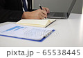 Manager notes the financial data summarized on the laptop computer in his notebook before meeting with the management. 65538445