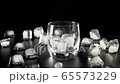 Cocktail concept. Camera moves forward on glass with ice on the black table with ice cubes on it against black background. Concept of alcohol cocktail party, nightlife and nightclub. Close up. 4K 65573229
