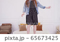 Happy girl having fun and jumping on white bed 65673425