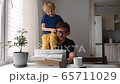 Man working from home with laptop during quarantine. Home office and parenthood at same time.  65711029