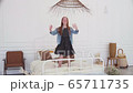 Happy girl having fun and jumping on white bed 65711735