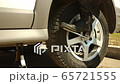Woman changes car wheel: unscrewing by wrench hard using legs 65721555