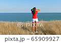 4K. Sexy  woman  in red blouse  Against  sea in summer day     65909927