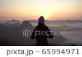 Young woman traveler looking at sea of mist and sunset over the mountain 65994971