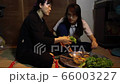 Mother and daughter sitting on the ground having Vietnamese style dinner in the darkroom. Poor 66003227