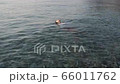Calm girl lying on water surface. Woman swims backstroke in sea. Young girl in white blouse relaxing and floating on back in water. Mountain view at sunset 66011762