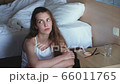 Young woman with long dark hair is sitting on the floor near the bed in a home environment. Girl grimaces, makes a funny face, blows a kiss, showing different emotions 66011765
