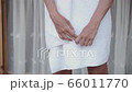 Female hands close up - anxiety, tension, embarrassment or impatience body language and hand gesture. Dressed in a white towel and stands outside close to home. Modesty, shyness 66011770