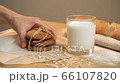 Beautiful oat biscuits in a stack next to a glass of milk on a light background 66107820