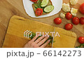 Top view female hands cuts dill with knife on cutting board, put it on sandwich with cucumber, tomato, arugula and whole wheat rye bread. Woman making vegan lunch. Fresh farm vegetable on wooden table 66142273