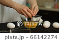 Woman breaking egg and it falls in glass bowl, in many broken eggs, yolk and protein. Whole eggs, eggshell, kitchen whisk on dark background. Cooking fried eggs, omelette, biscuit dough, pastry, pasta 66142274