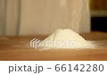 Flour sprinkles on table and form hill. Preparation to bake, kneading dough in bakery or home kitchen. Baking ingredient. White powder, ground wheat falls down. Making pastry, bread, cake, pasta meal 66142280