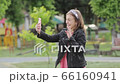 Beautiful young girl with dark curly hair using her cell phone, outdoor. The blogger girl is broadcasting. 66160941