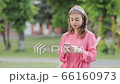 Pretty Young Woman Walking in the Park. Using her Mobile Phone. Chatting on it. Typing a Message. 66160973